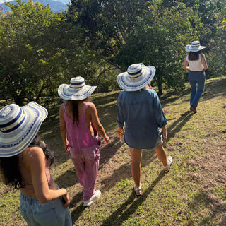 People wearing sun hats in a field with trees and blue sky in the background